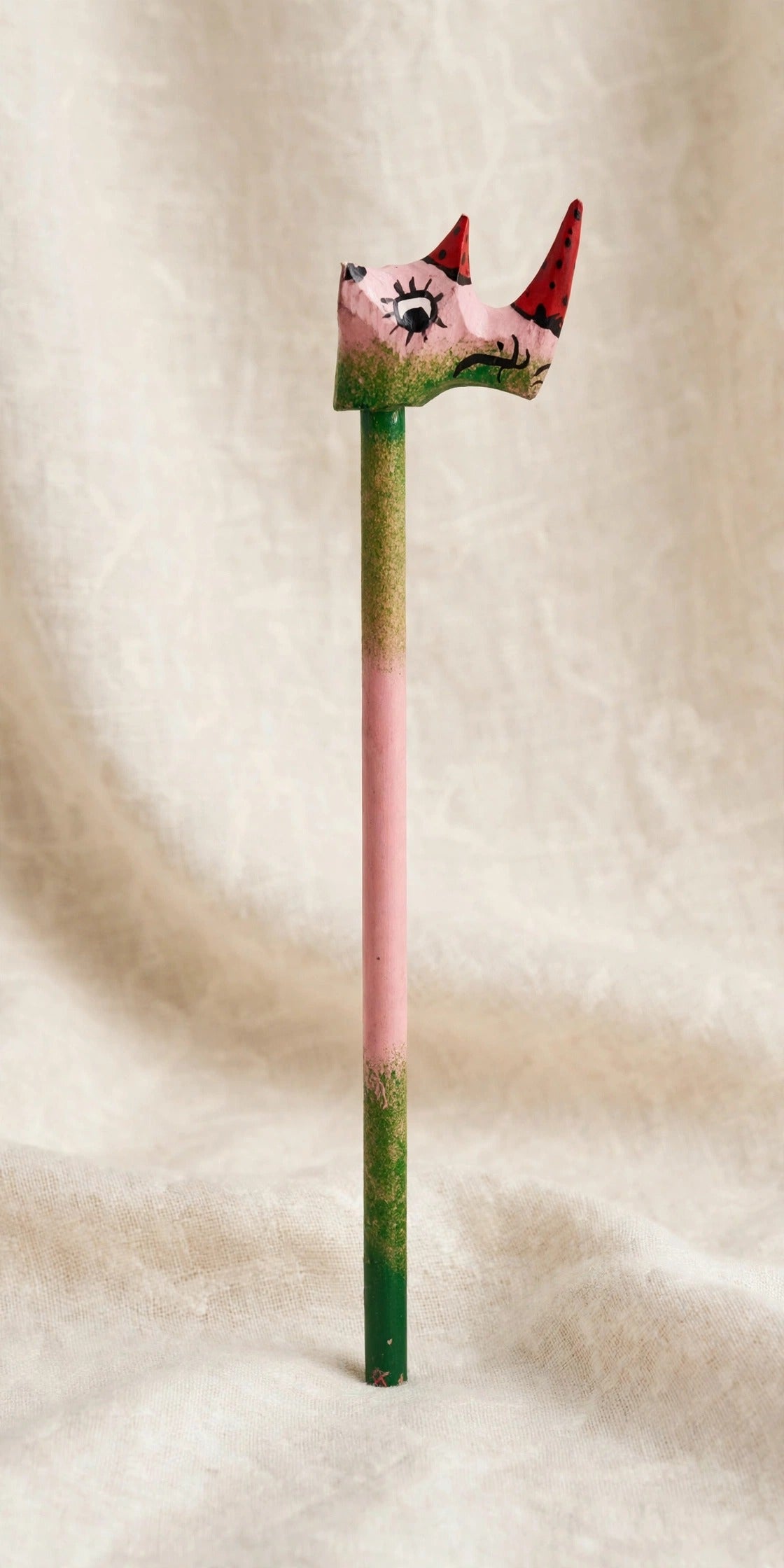 Hand-carved wooden pencil with a pink rhino head with two red horns, third view