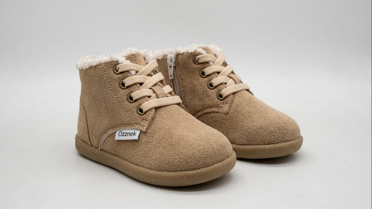 Pair of tan children's boots with a visible brand label on a light gray background