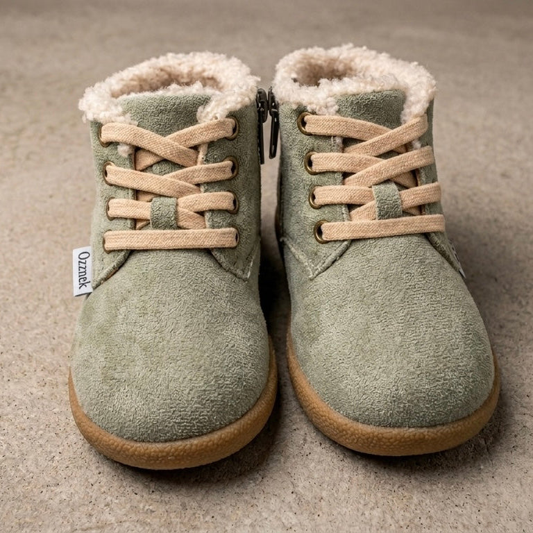 Pair of green boots with fur lining on a beige carpet