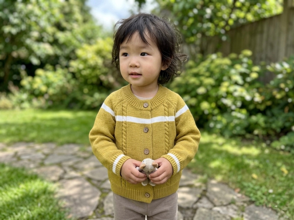 Child wearing a yellow sweater with white stripes outdoors