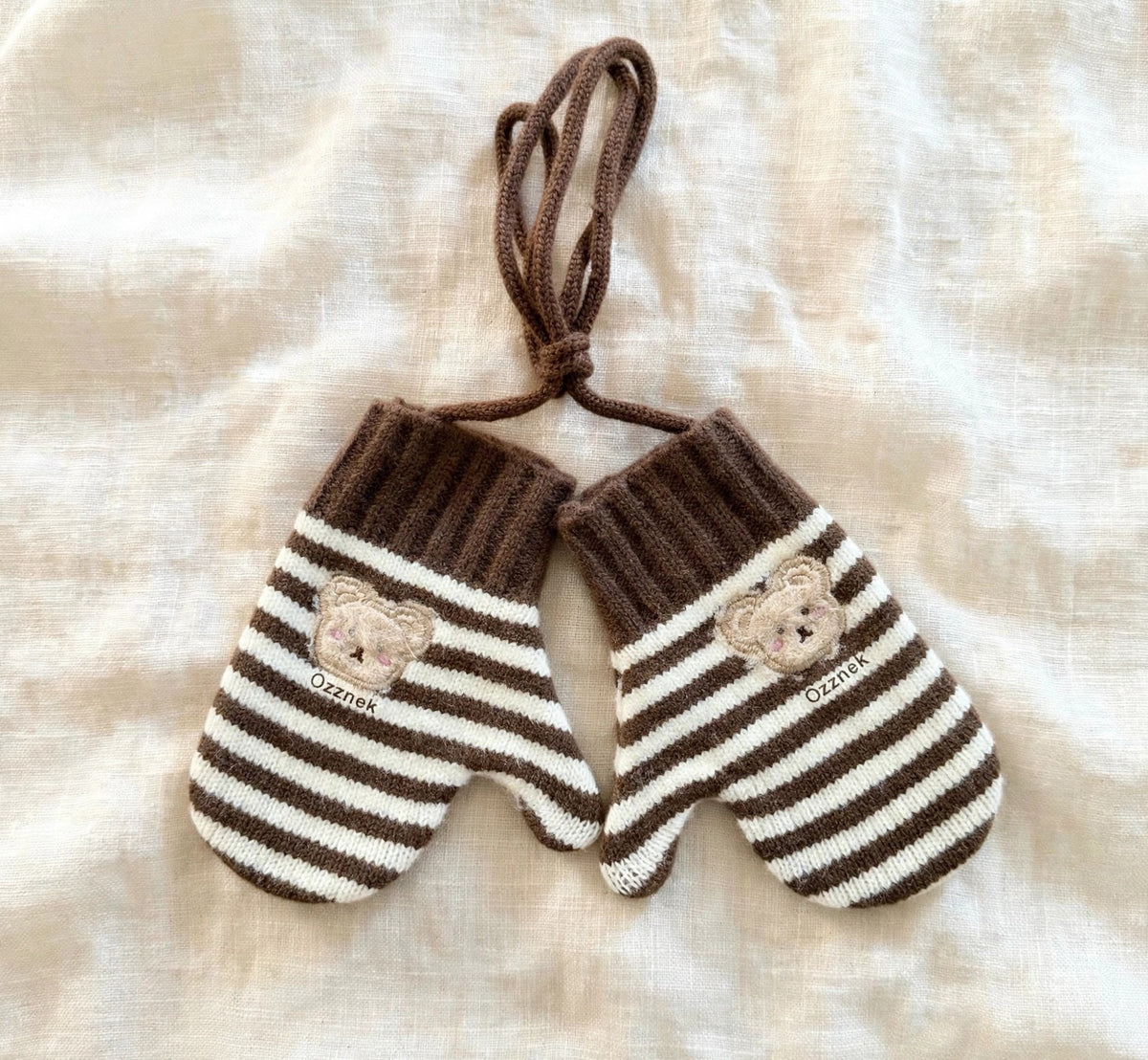 Kids winter gloves with string — pair of brown striped gloves on cream linen | Ozznek