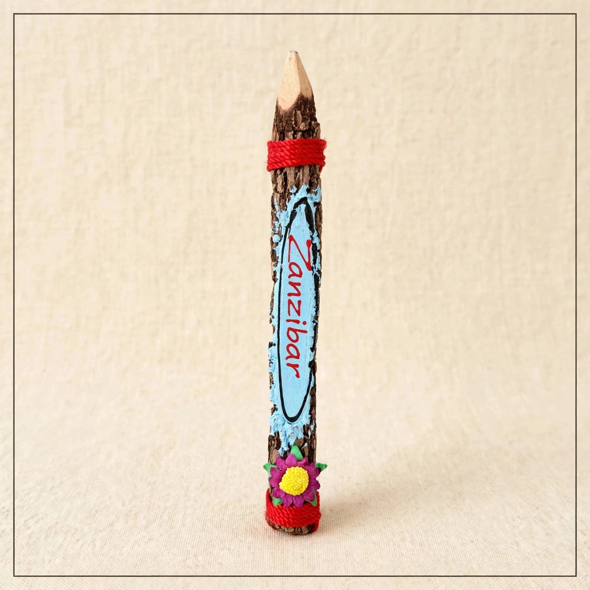 Big light blue hand-carved wooden coloring pencil with red twine and the hand-painted word Zanzibar
