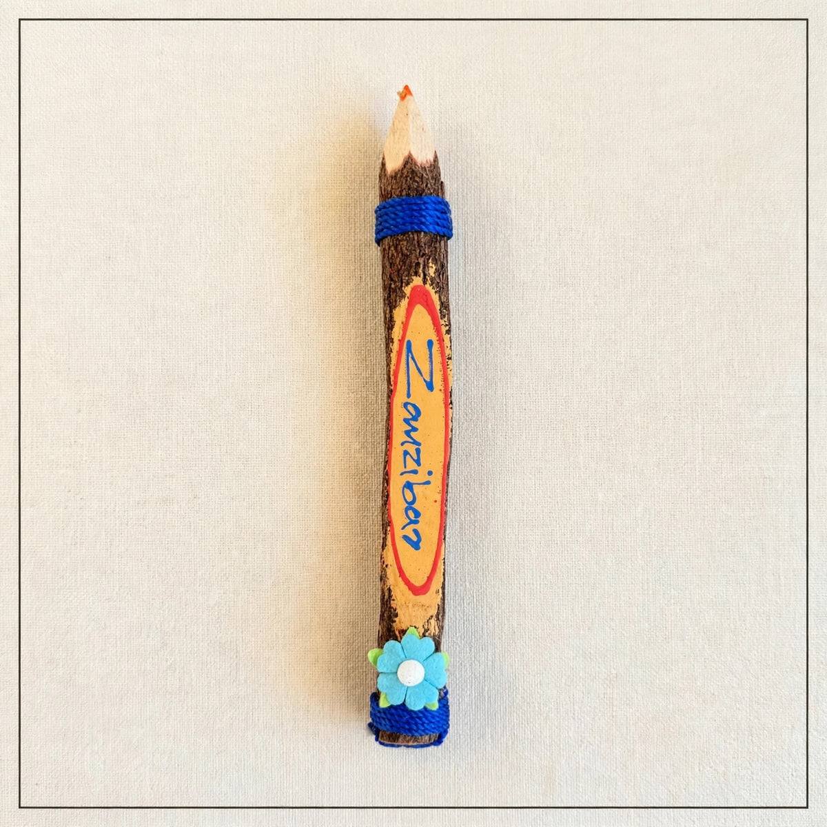 Big hand-carved wooden coloring pencil with blue twine, the hand-painted word Zanzibar and a bright orange tip