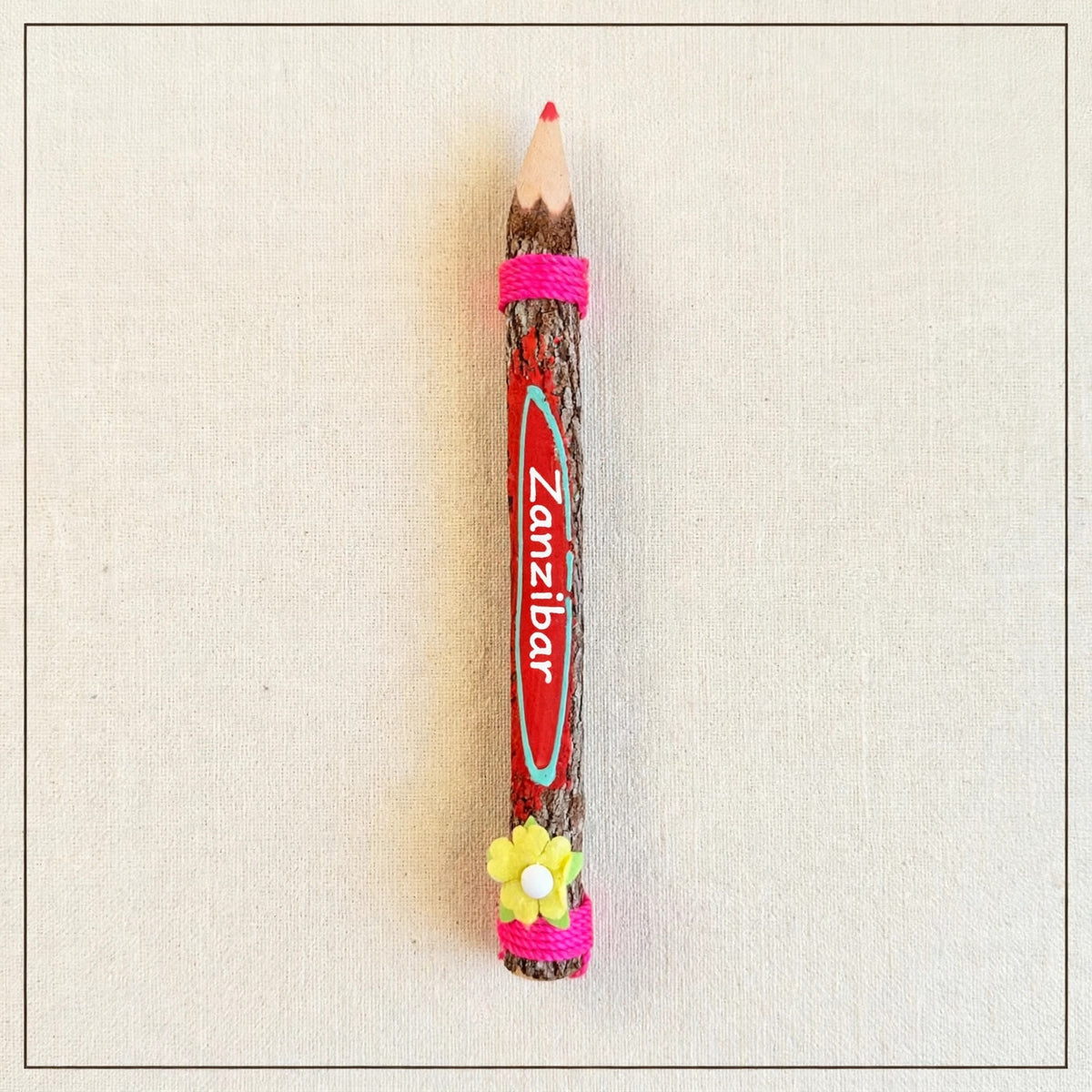 Big red hand-carved wooden coloring pencil with pink twine and the hand-painted word Zanzibar, pink tip