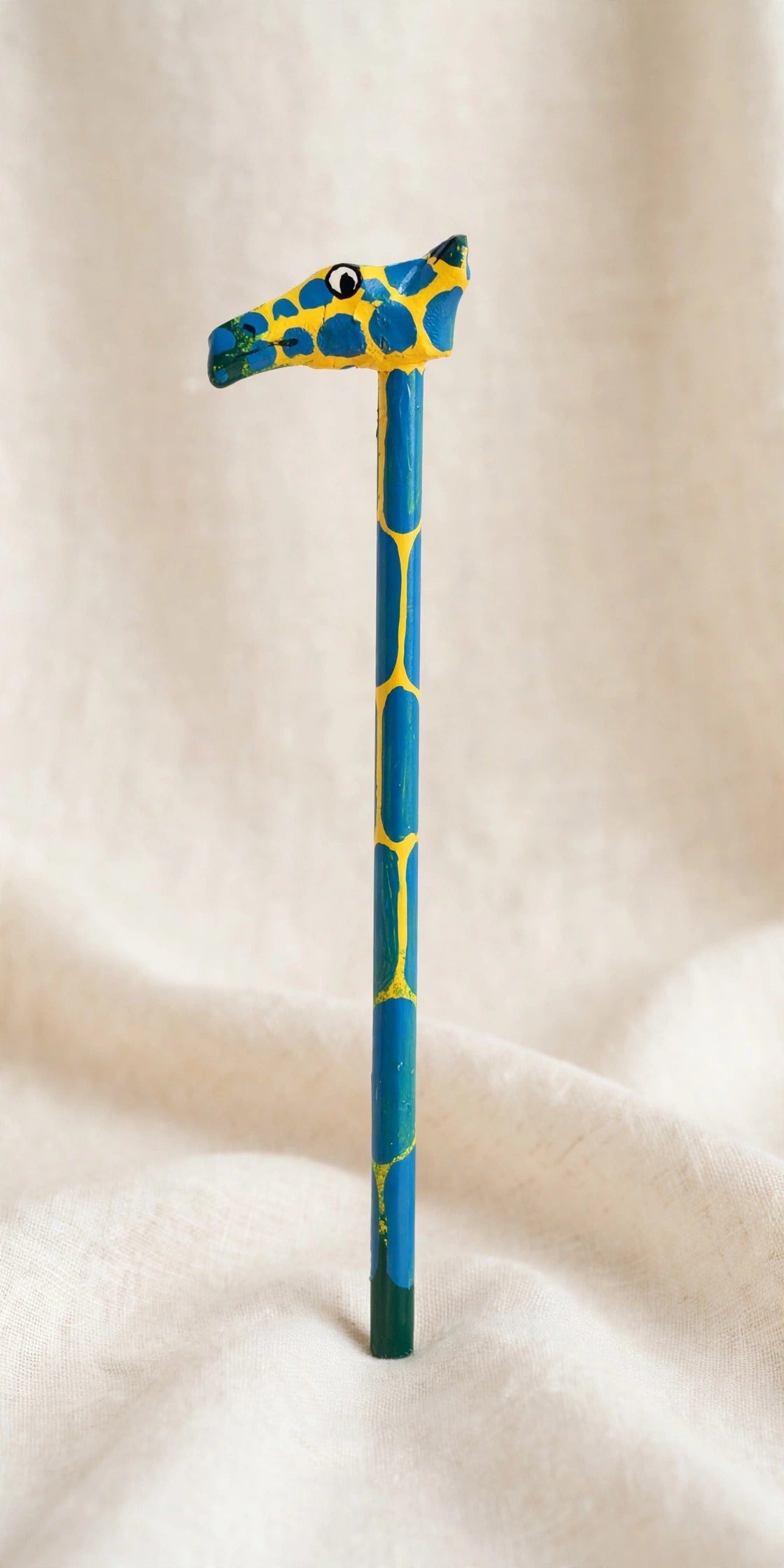 Hand-carved wooden pencil with a yellow giraffe head with blue spots, handmade in Zanzibar