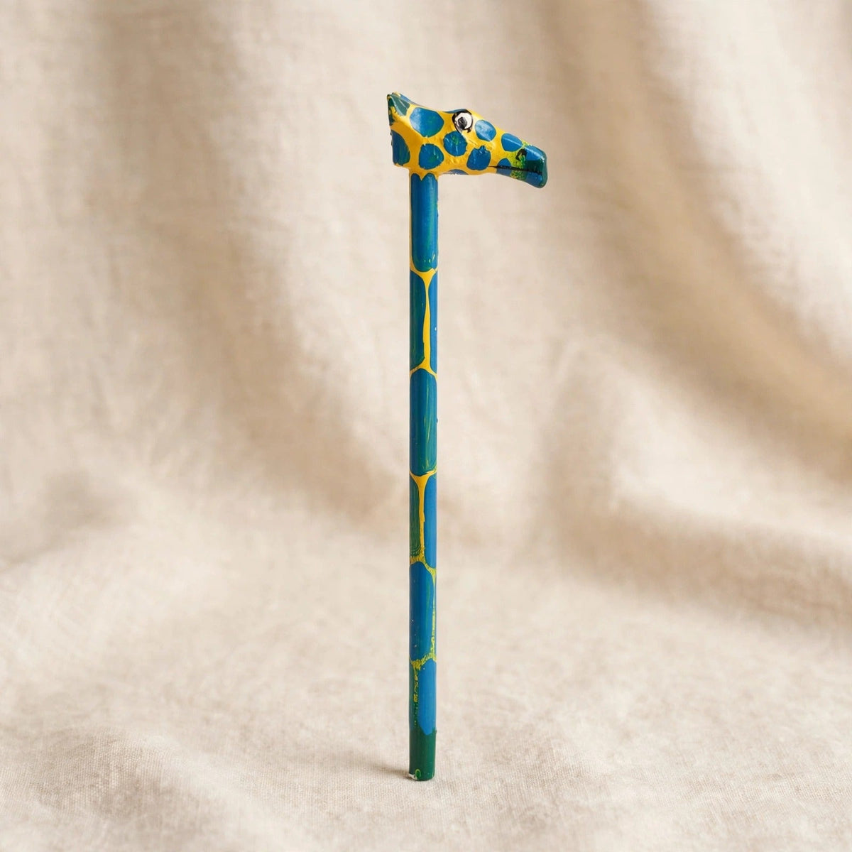 Hand-carved wooden pencil with a yellow giraffe head with blue spots, third view