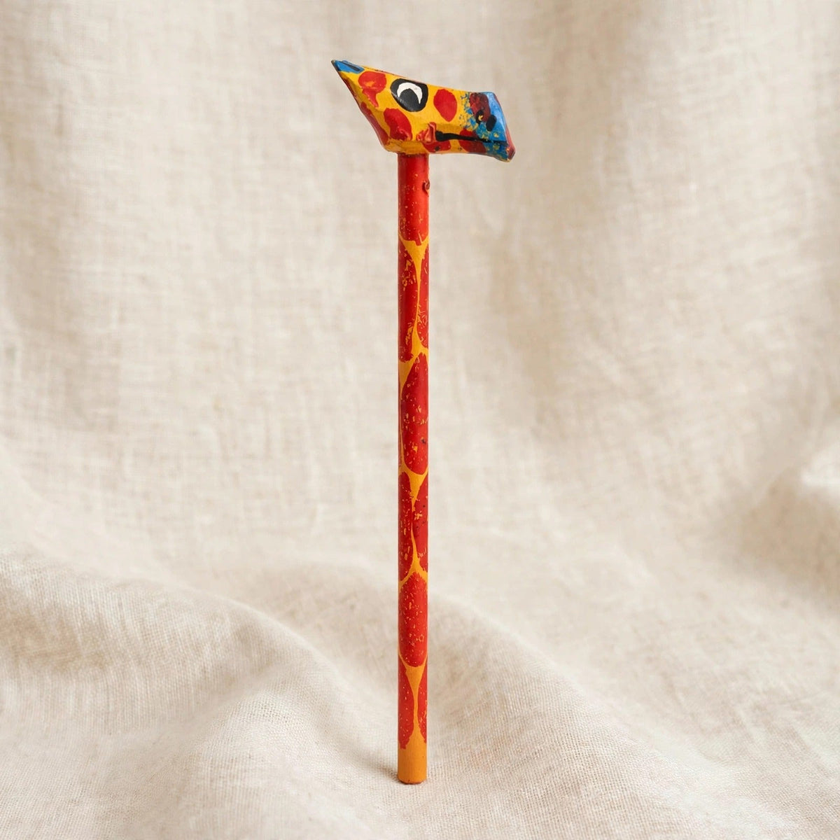 Hand-carved wooden pencil with a yellow giraffe head with red spots, handmade in Zanzibar