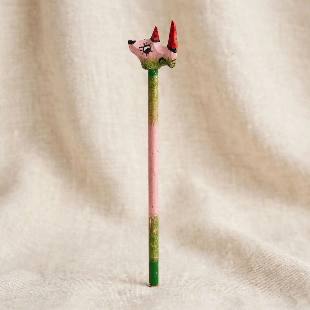 Back view of a hand-carved wooden pencil with a pink rhino head with two red horns