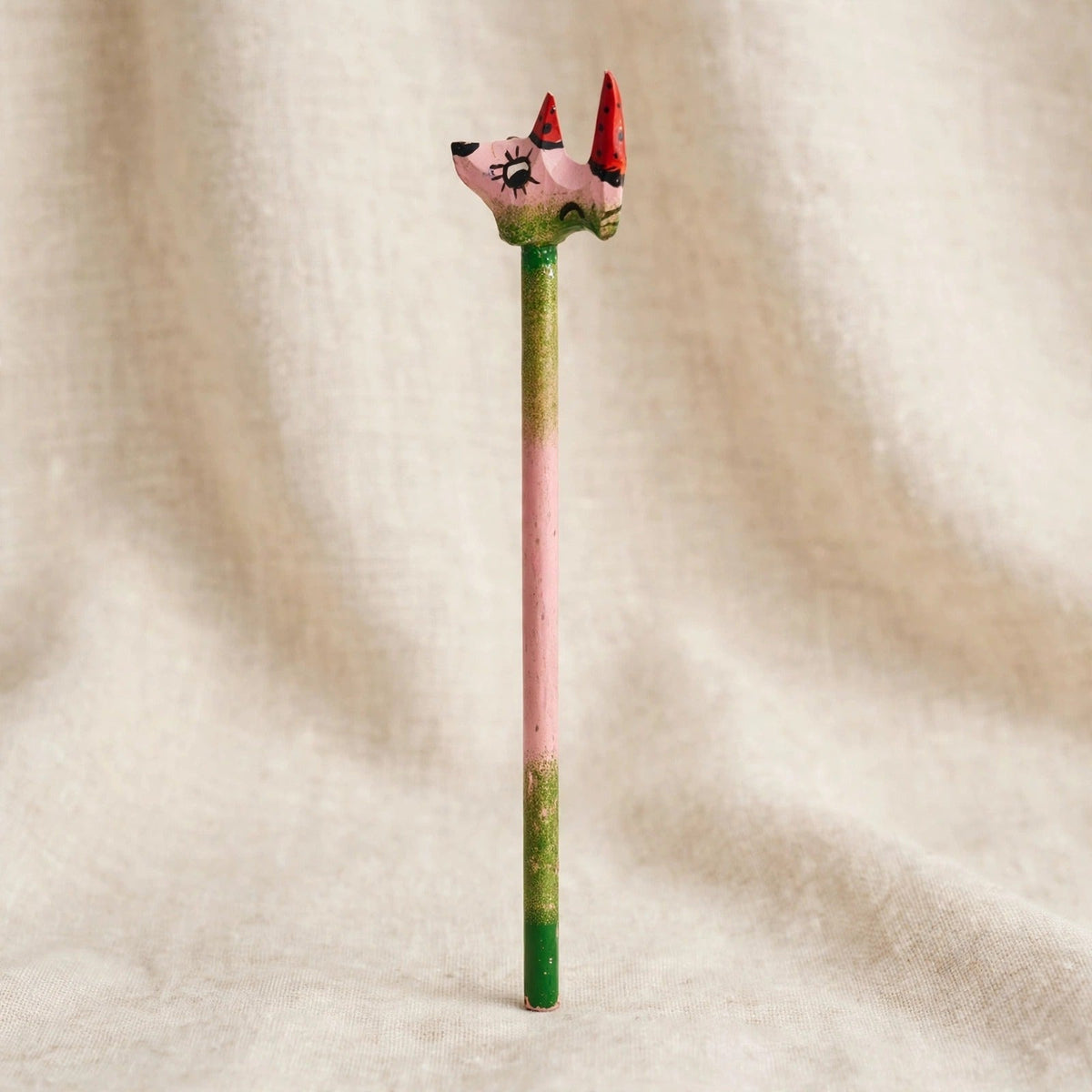 Back view of a hand-carved wooden pencil with a pink rhino head with two red horns