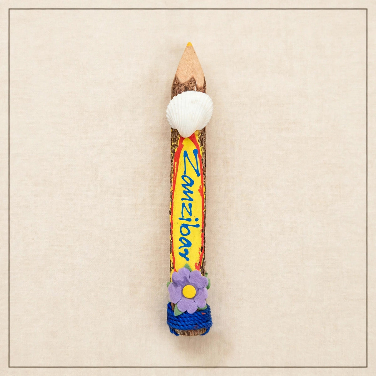 Small yellow hand-carved wooden coloring pencil with a real seashell and the hand-painted word Zanzibar