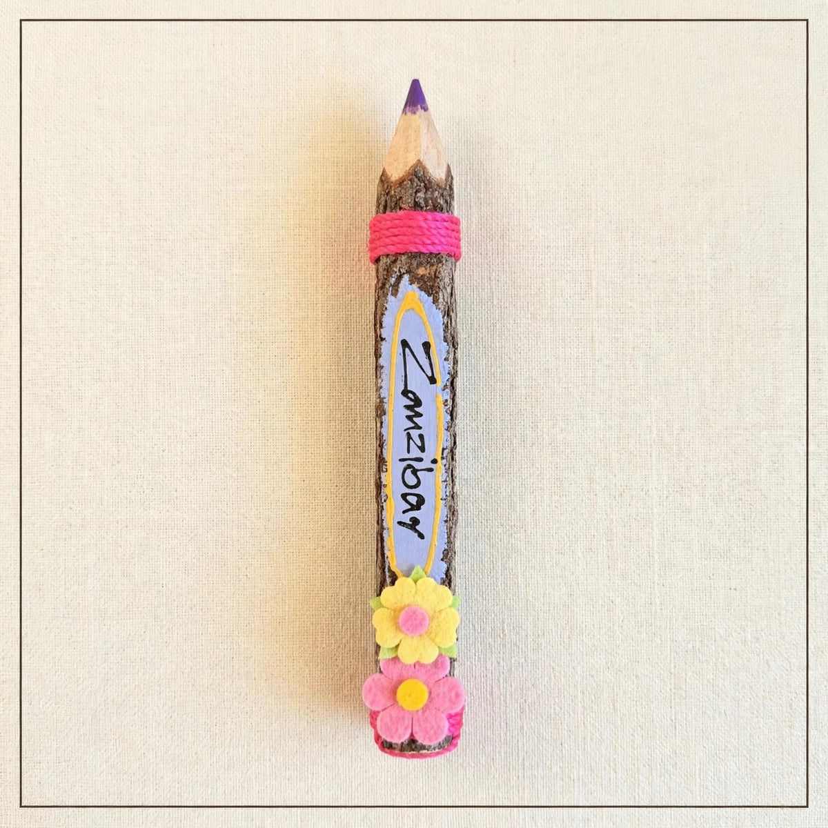Purple big hand-carved wooden coloring pencil with natural bark and the hand-painted word Zanzibar