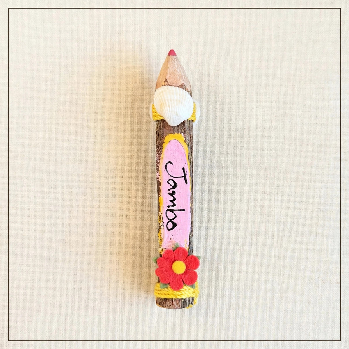 Pink small hand-carved wooden coloring pencil with a real seashell and the hand-painted word Jambo